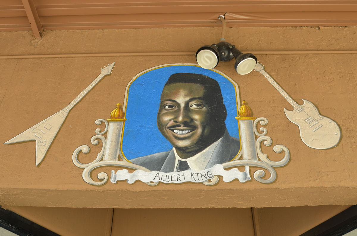 portrait of Albert King (head shot) on the outside of a guitar store 