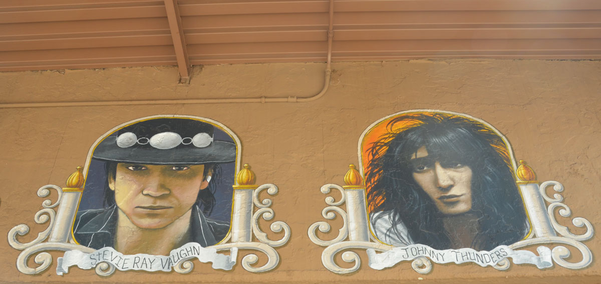 portraits of two guitar players (head shots) on the outside of a guitar store - Stevie Ray Vaughan and Johnny Thunders 
