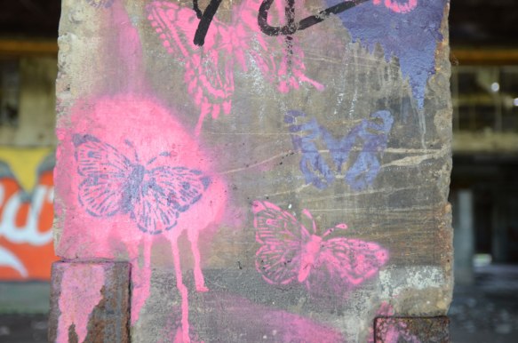 pink and purple stencilled butterflies on a concrete post 