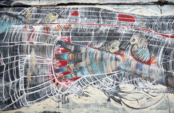 middle part of a long mural of a woman lying down, her hand is in her pocket which is also a bird nest. Five or six birds are in the picture, a couple tucked under her arm, some lying on her.