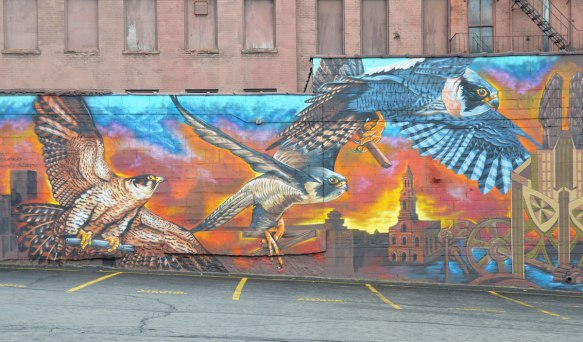 part of a mural, falcons flying over a city skyline at sunset