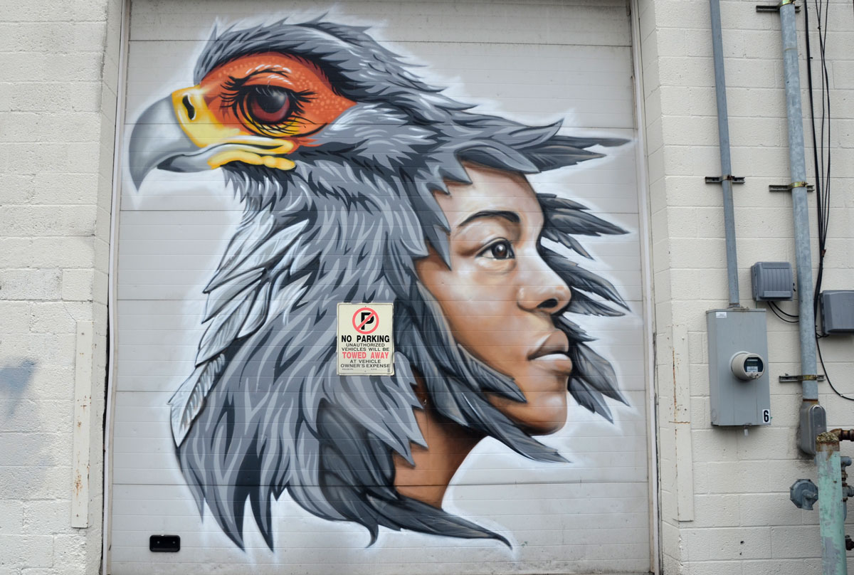 mural of a boy and a bird. The bird is sitting on the boys head such that the feathers of the bird look like the boys hair. 