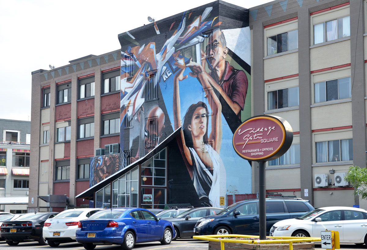 large mural of active people over the front entrance of a three storey building, 