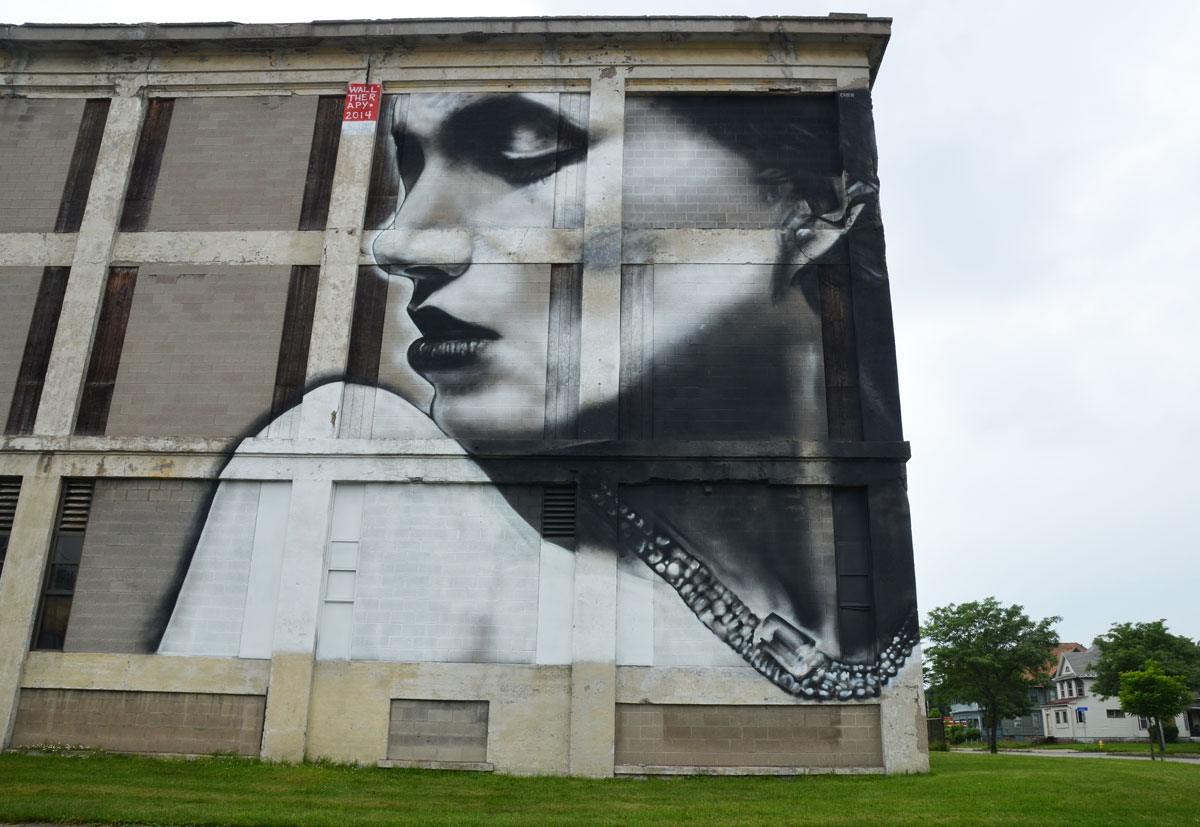 Wall Therapy mural in Rochester, on the side of a building, a three storey high black and grey woman looking over her shoulder
