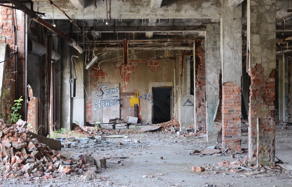 crumbling brick pillers in front of a wall on which someone has written Slime heads 