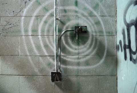 a large spiral made with spray paint on a concrete block wall 