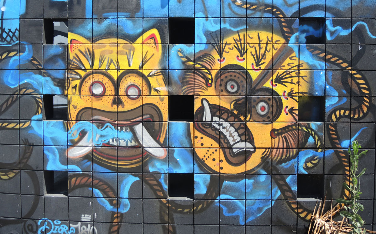 street art of two yellow animal masks, one is feline and the other may be monkey. South American looking in the design and markings on the masks. 