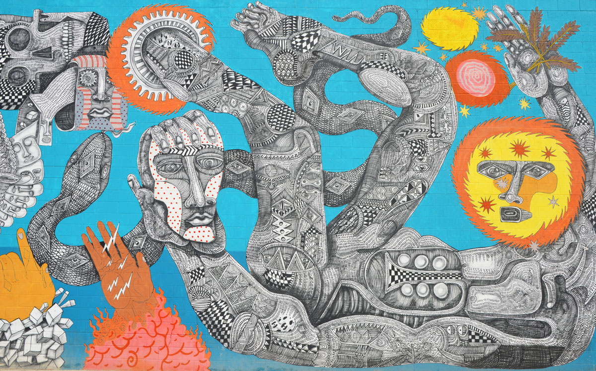part of a large mural by Zig Ziegler on a wall, intricate black line drawings on white of faces, people like creatures, trees, skulls, gears, feets, etc. on a sky blue background. Some yellow and orange features for contrast, sun, hair, circles 
