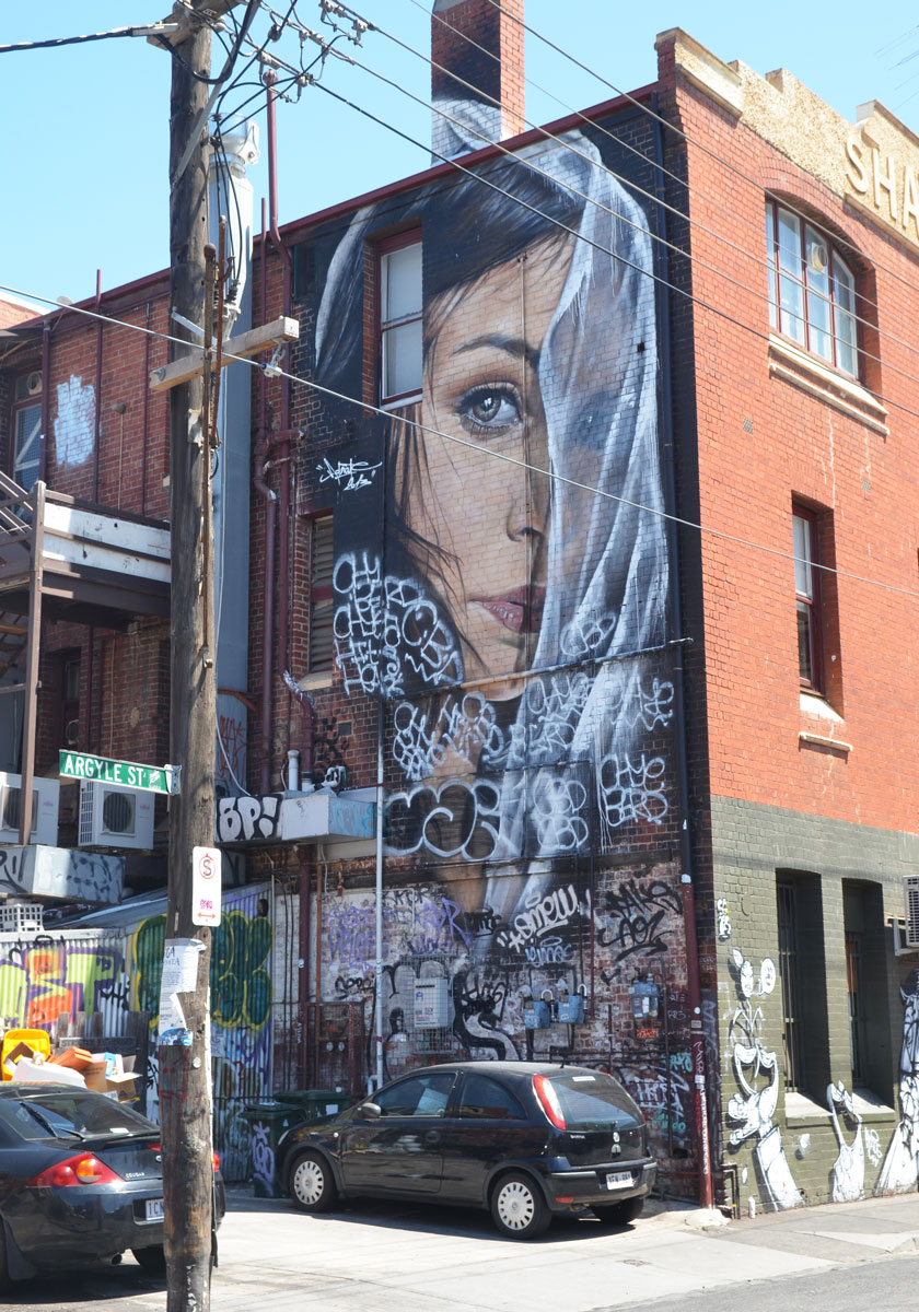 A mural by Adnate on Argyle Street of a woman's head, partially in profile, and partially hidden behind a thin white veil 