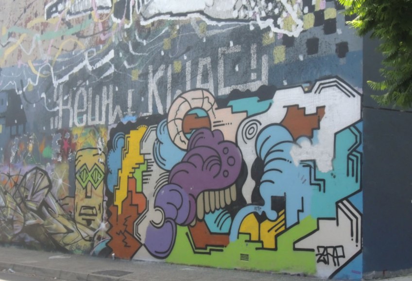 mural of blobs and shapes in different colours on a wall in an alley
