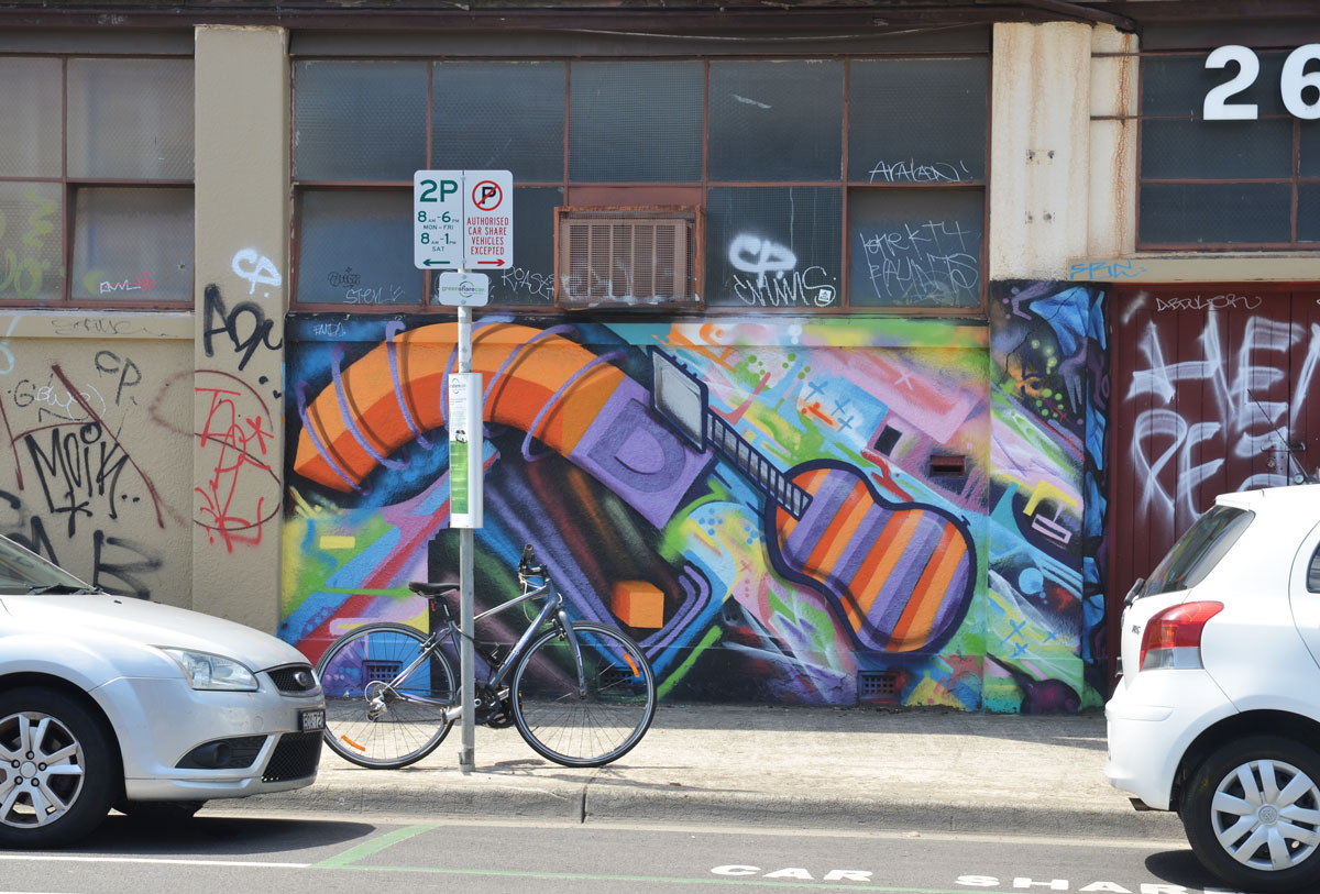 mujlti coloured mural that includes an orange and purple guitar. A bike is parked in front of the mural 