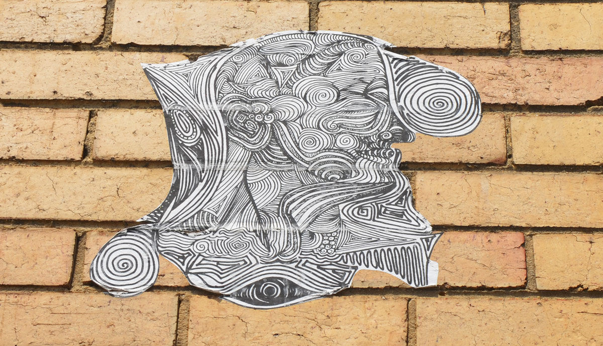 black and white wheatpaste high on a yellowish brick wall 