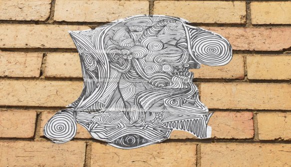 black and white wheatpaste high on a yellowish brick wall 