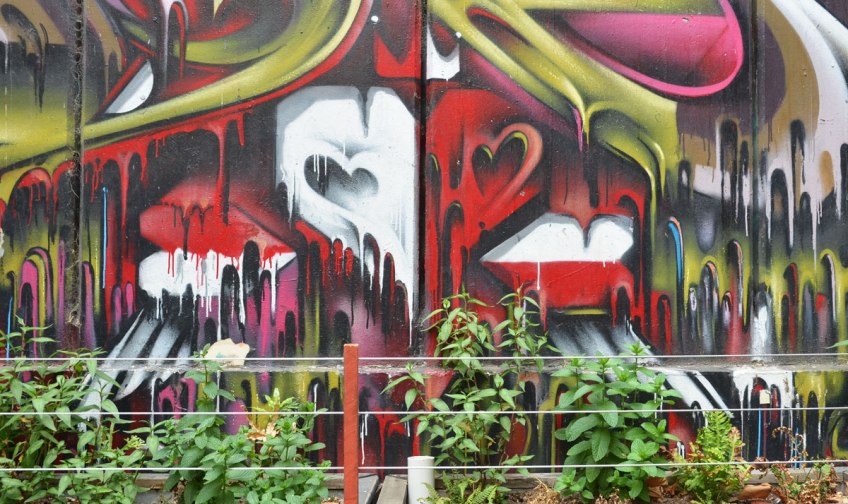 the bottom part of a mural behind a row of plants. heart shapes in red and white with paint dripping downwards