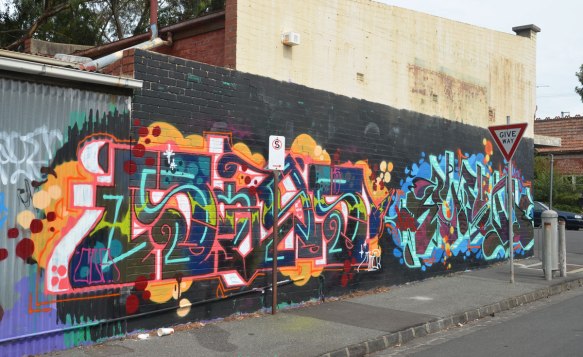 tag graffiti, two pieces, on a wall beside a side walk