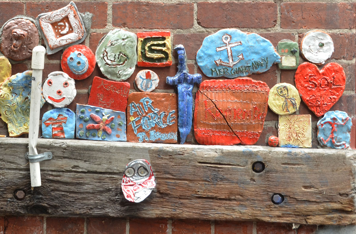 many clay pieces, a sword,an anchor, some with words, attached to a wall, part of a Legacy project for ANZAC commemoration