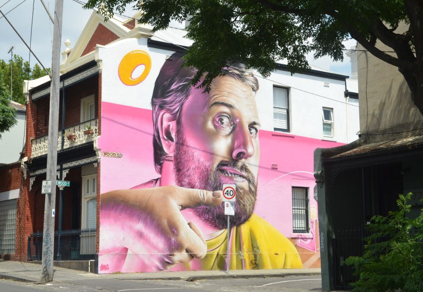 view of a street, houses with a mural on it, a man from the shoulders up