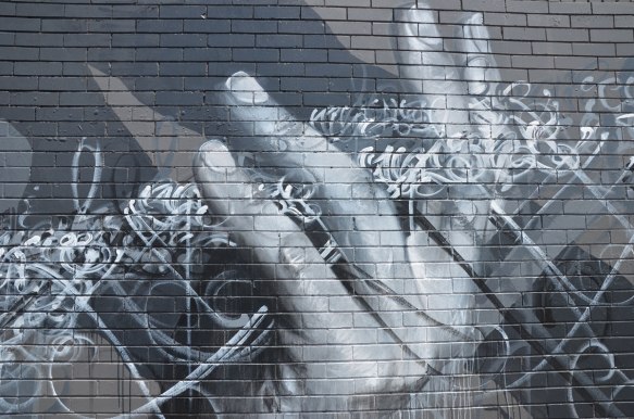 monochromatic painting in  greys of a hand on a large mural