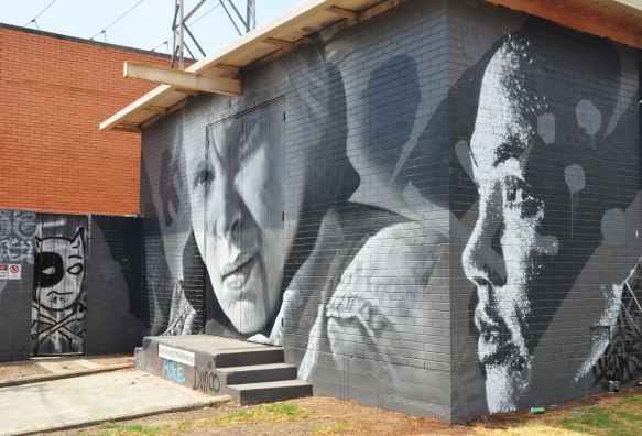 monochromatic realistic portrait of two women part of a larger mural painted on a wall surrounding a power substation in Melbourne