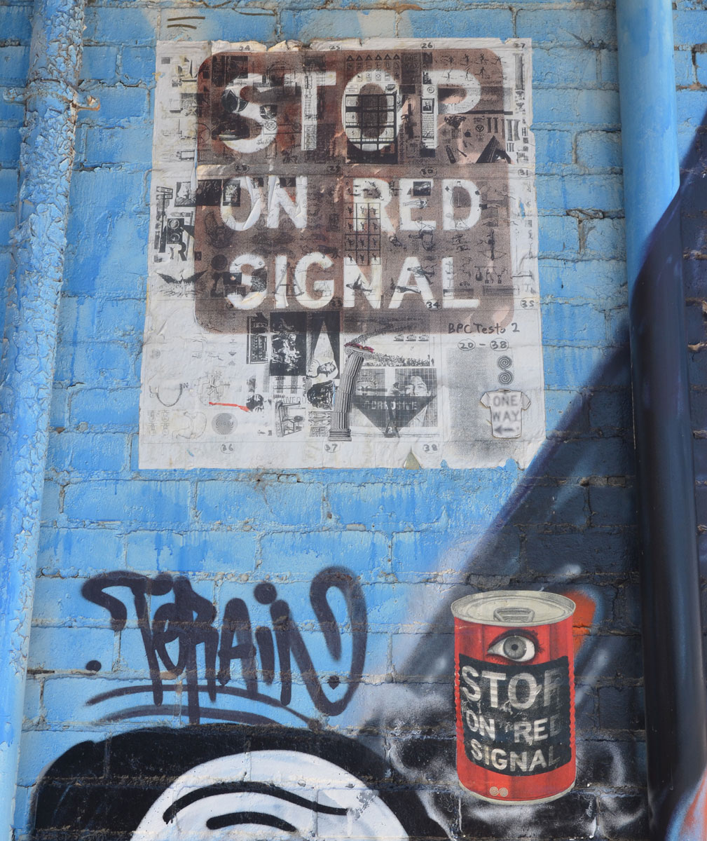 A skateboard shaped white paste-up with a drawing of bin Laden overlayed with the words An Eye for An eye blinds us both. 