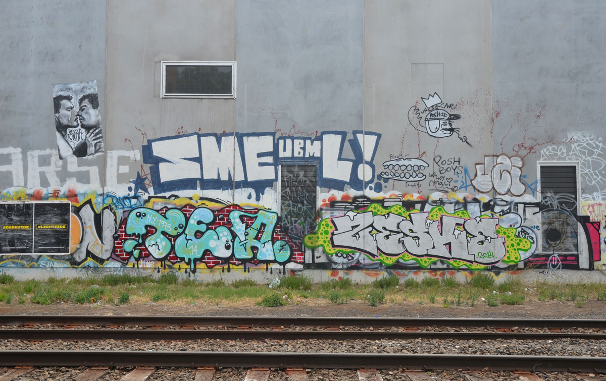 concrete wall with tags, tea, zeske, smeumbl, posh boys. Plus black and white wheatpaste of two men kissing.