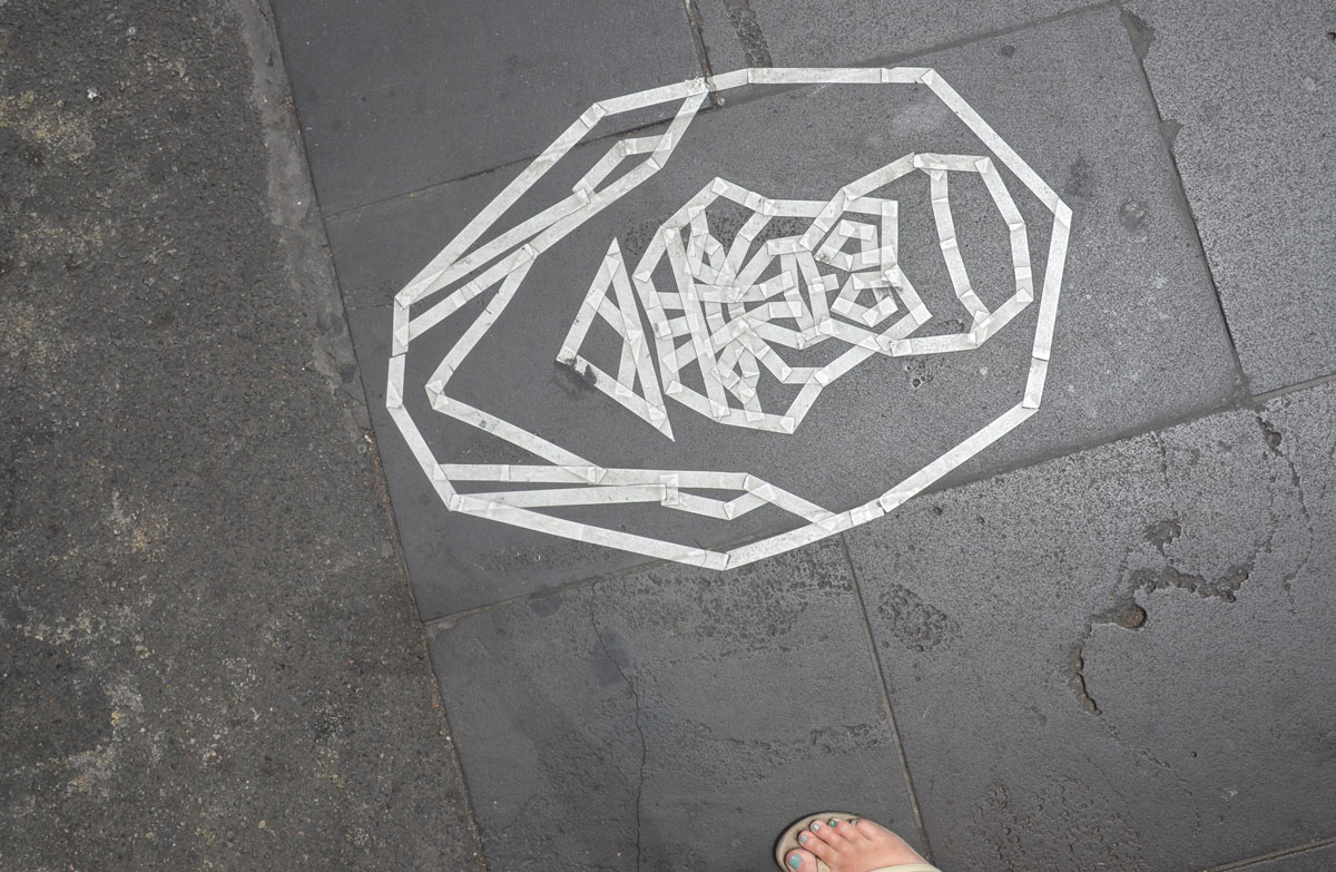 white sticky tape face-like creation on the pavement 