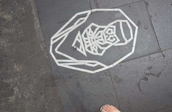 white sticky tape face-like creation on the pavement 