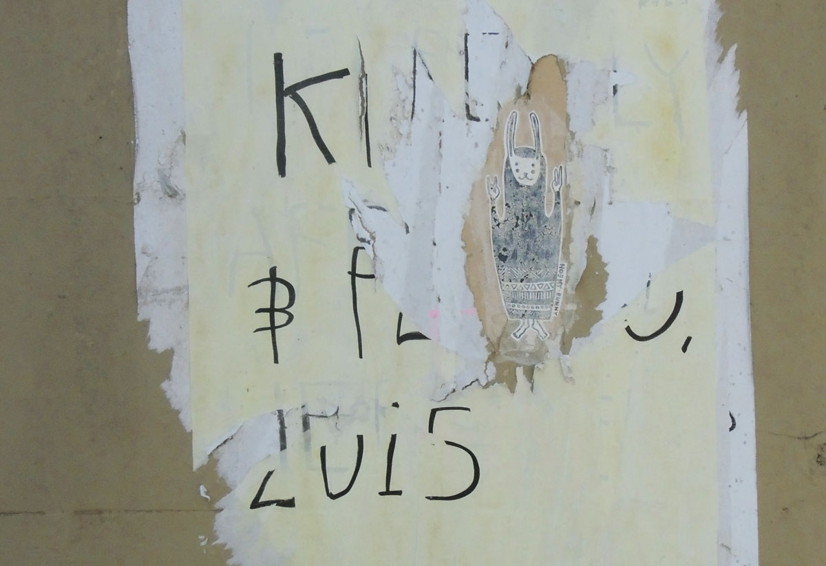 old, ripped past-up that had words on it, a hole it in reveals a drawing of a person underneath