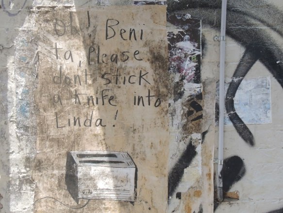 poster on wall that says Oh Benita please don't stick a knife into Linda. A picture of a toaster is below the words. 