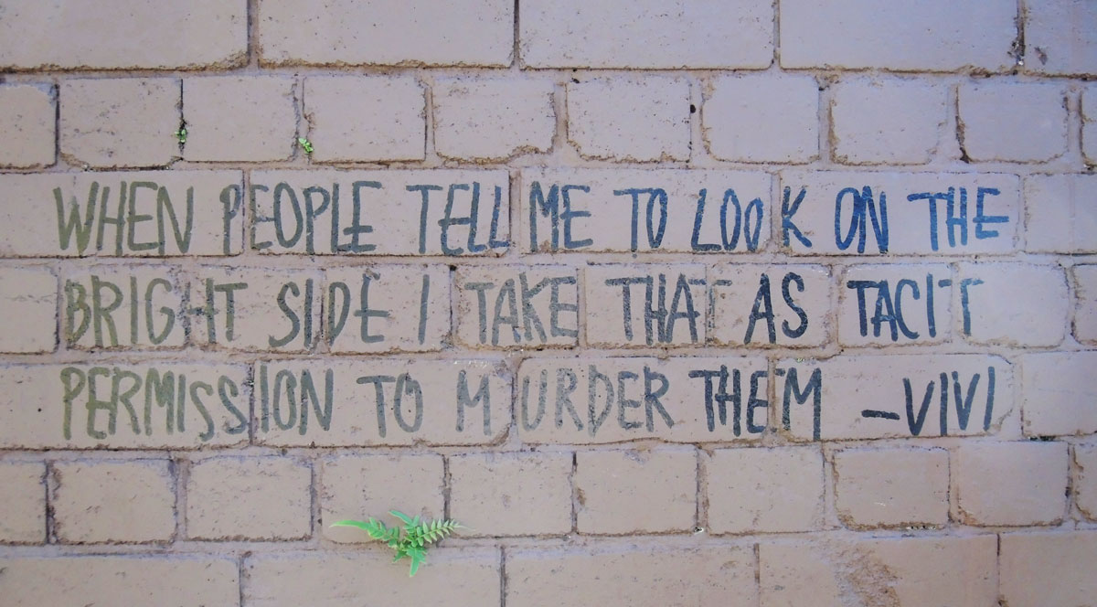 words written in block letters, black marker on brick wall "When people tell me to look on the bright side I take that as a tacit permission to murder them. Vivi"