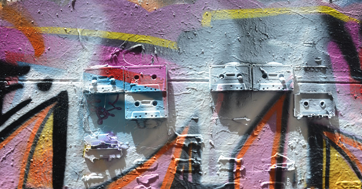 5 old cassette tapes are mounted on a wall and then covered with spray paint as part of a street art piece in Melbourne