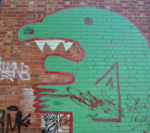 green monster street art painting on a brick wall 