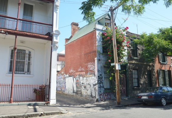 entrance to Bach Lane, street sign, two storey brick buildings on either side 
