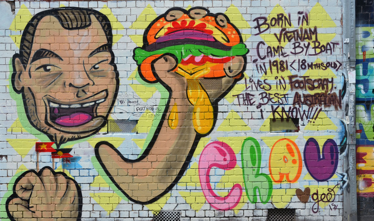 mural of a person holding a messy sandwich in his hands, with some words that say: Born in Vietnam came by boat in 1981 (18 months old) lives in Footscray the best Australian I know 