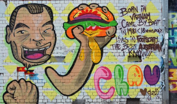 mural of a person holding a messy sandwich in his hands, with some words that say: Born in Vietnam came by boat in 1981 (18 months old) lives in Footscray the best Australian I know 