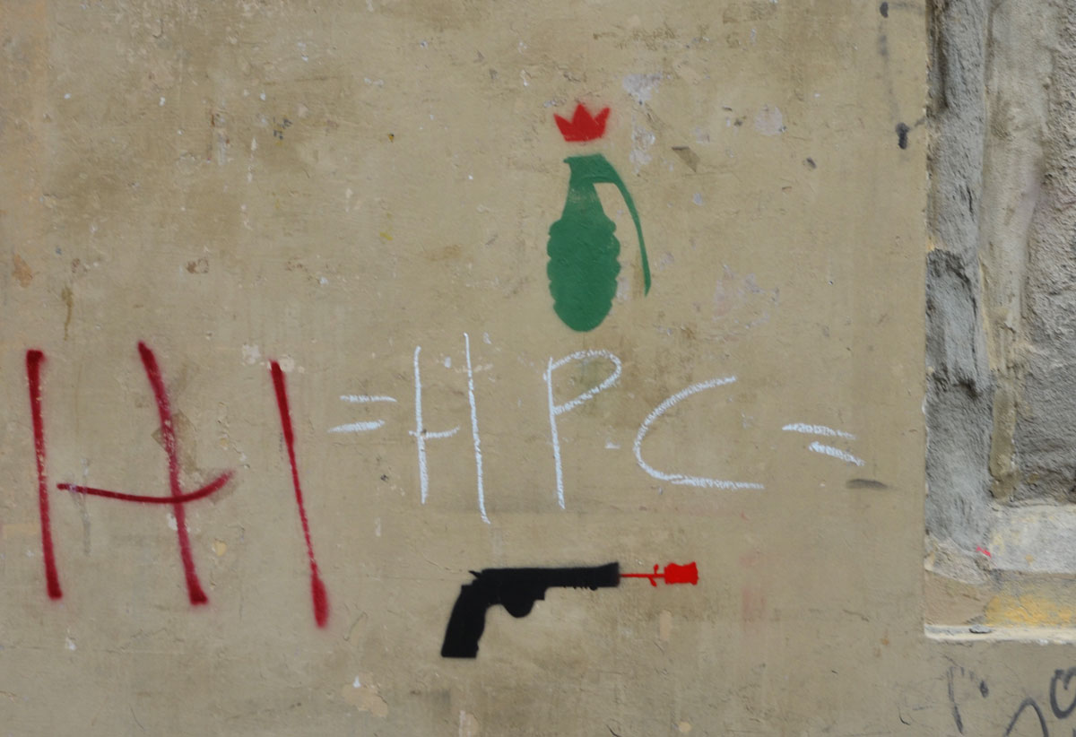 Two small stencils on a wall, a green hand grenade and a black handgun, 