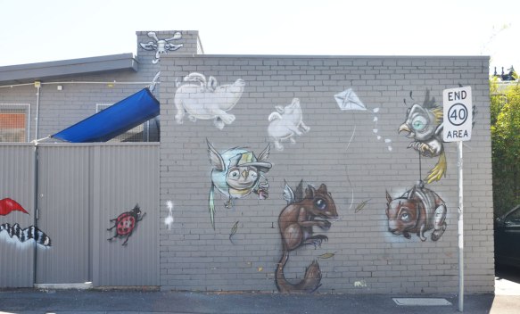 a mural of an assortment of animals on a grey wall. a ladybug, two flying pigs,