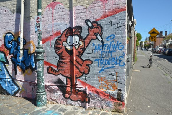 street art mural of Garfield the Cat holding a marker and writing on the wall, Nothing but Trouble