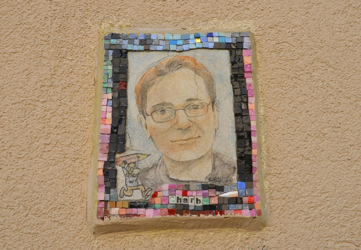 small portrait of a man on a wall.  Hand drawn head and shoulder shot, framed with tiny pieces of mosaic tile - Charb