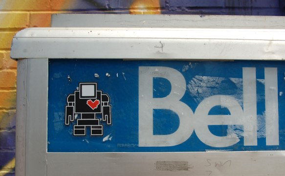 black lovebot sticker on the blue part of a Bell payphone