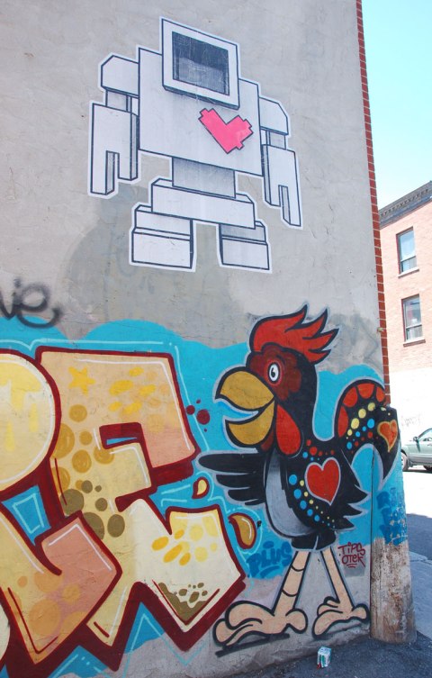 large wheatpaste paste up lovebot on a wall about a street art painting of a rooster who also has a heart on his body