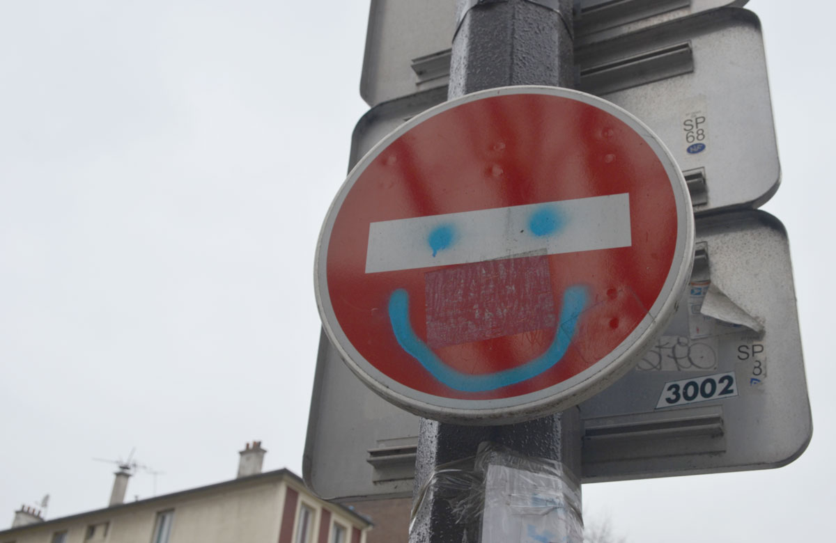 graffiti altered no entry sign, red circle with a white horizontal bar - added blue spray paint happy face