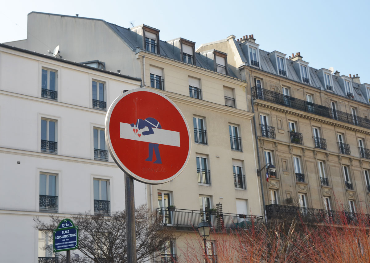 graffiti altered no entry sign, red circle with a white horizontal bar - added a policeman leaning over it, with hearts