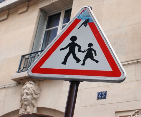 graffiti altered triangular sign of two kids running while holding hands, a finger is pointing at them, through clouds from the top of the triangle