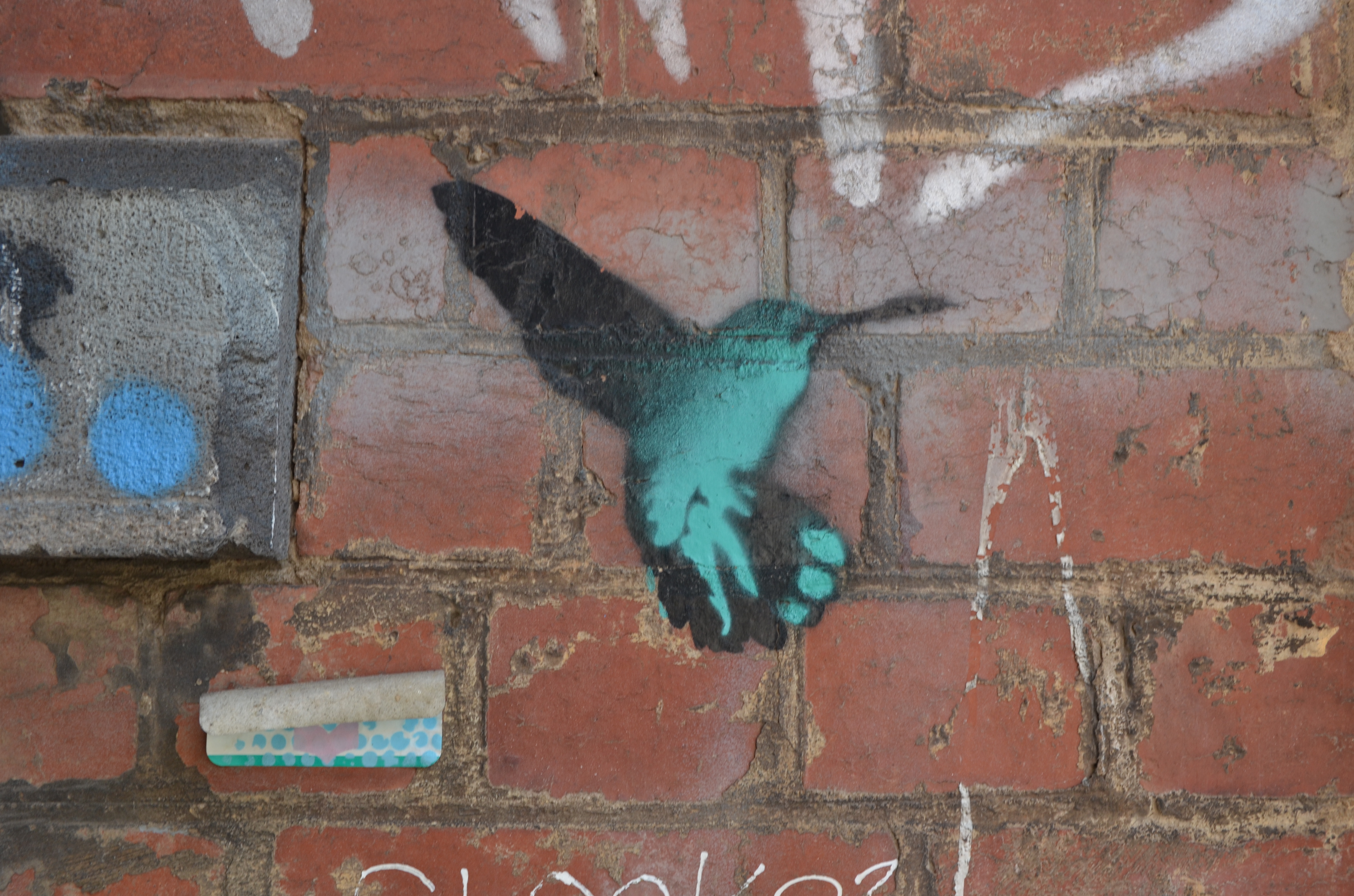 a stencil in teal and black of a hummingbird hovering