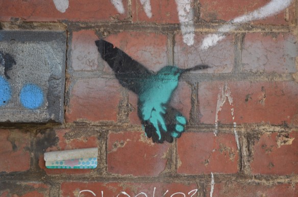 a stencil in teal and black of a hummingbird hovering