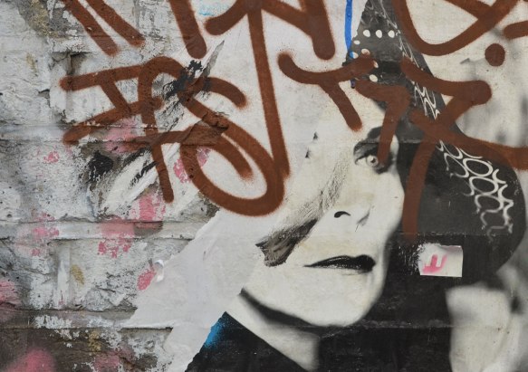 street art picture of a woman's face partially obscured by a brown tag