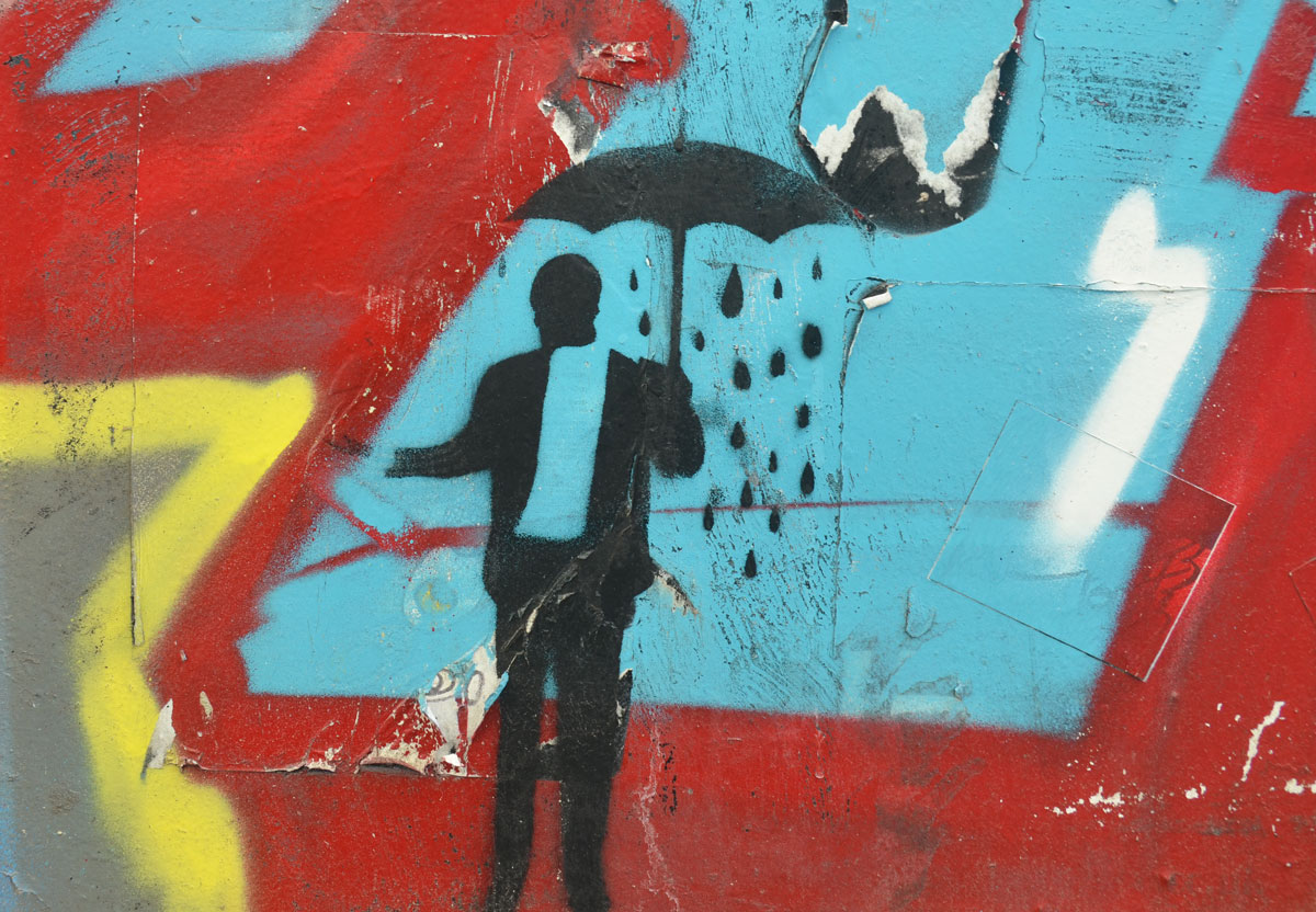 stencil of a man holding an umbrella, It is raining under the umbrella but not outside of it. Man is holding hand out to see if it is still raining.