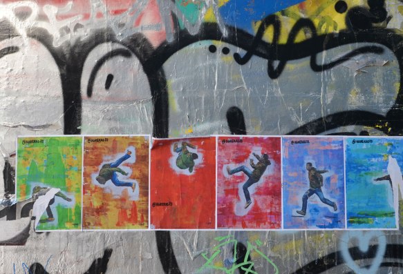 a row of posters showing a man in various jumping poses, each with a different coloured background, green, orange, red and blue. 