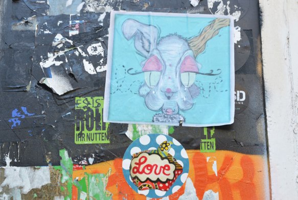 a square paste up of a rabbit's head and a circular paste up below it, white polka dots on blue with the word love written in cursive in the center. 